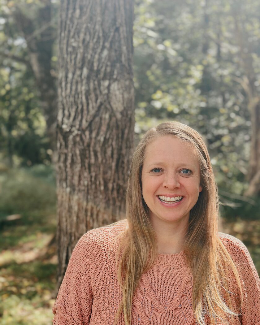 The founder of Homegrown Learning Studio smiling in a sunlit wood
